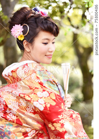 A woman wearing a color coat in a Japanese garden 75800486