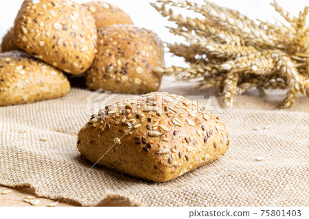 Home baked bread. Rye bakery with crusty loaves and crumbs. Fresh rustic traditional bread with wheat grain ear or spike plant on natural cotton background. Design element for bakery product label. 75801403