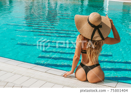 Summer pool relaxing. Young sexy woman in Sun hat, bikini swimsuit, sunglasses swimming in blue water. Trendy summer concept. 75801404