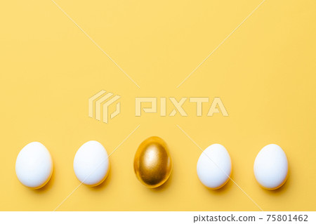 Easter decoration. Golden, white colour egg on pastel yellow background in Happy Easter decoration. Foil minimalist egg design with copy space. 75801462