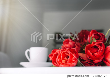 Bouquet of red tulips on table and white coffee cup. Concept for greeting card Bouquet of red tulips on table and white coffee cup. Concept for greeting card 75802178