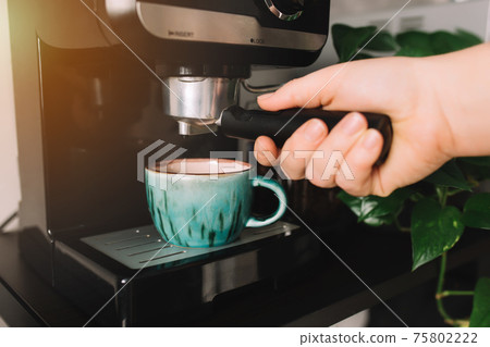 Hand holding portafilter, coffee cup, coffee maker machine, coffee time 75802222