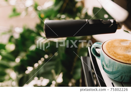 Green cup of coffee at the coffee maker machine, coffee time. Blurred background Green cup of coffee at the coffee maker machine, coffee time. Blurred background 75802226
