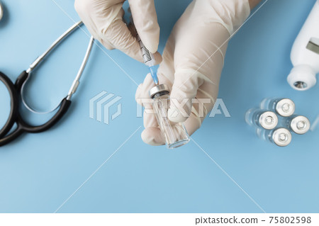 Doctor hands holding bottle with vaccine and syringe, thermometer, stethoscope 75802598