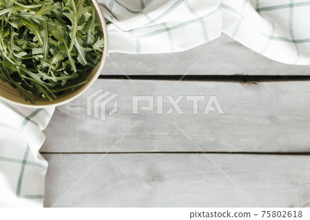 Green arugula salad leaves in bowl on wooden background. Healthy eating concept Green arugula salad leaves in bowl on wooden background. Healthy eating concept 75802618