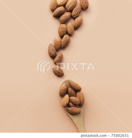 Raw almond kernels in spoon, beige background. Cosmetic, healthy food concept 75802631