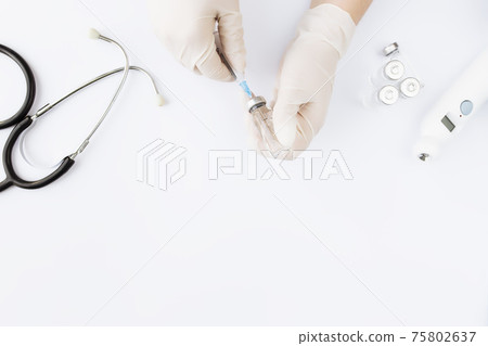 Doctor hands holding bottle with vaccine and syringe, thermometer, stethoscope Doctor hands holding bottle with vaccine and syringe, thermometer, stethoscope 75802637