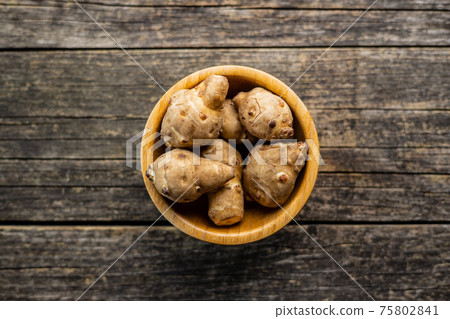 Raw jerusalem artichoke. Topinambur vegetable root in wooden bowl. Raw jerusalem artichoke. Topinambur vegetable root in wooden bowl. 75802841