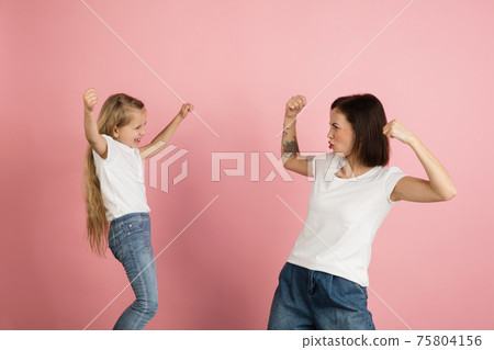 Happy woman and little girl, mother and daughter isolated over pink background. 75804156