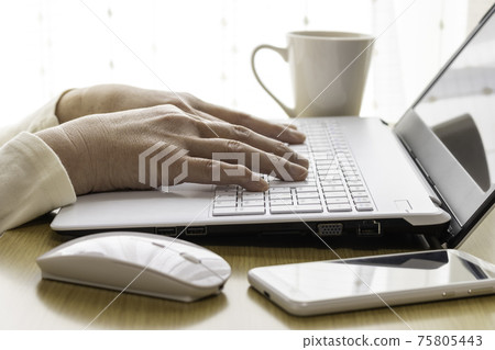 Image of a senior woman working on a computer at a table at home (Japanese, 60s) 75805443