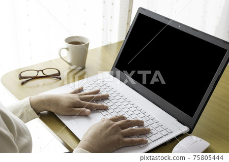 Image of a senior woman working on a computer at a table at home (Japanese, 60s) 75805444