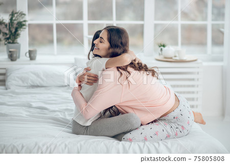 Mom and daughter hugging on bed in morning Mom and daughter hugging on bed in morning 75805808