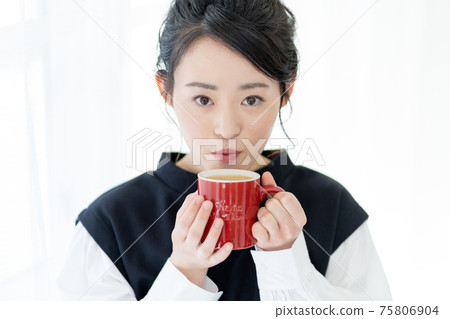 Face up of a young woman drinking cafe au lait in a red mug 75806904