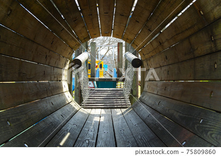 Composition where you can see the outside scenery from inside the round tunnel of wooden playset in the park 75809860