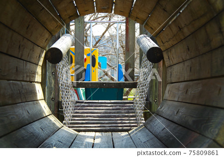 Composition where you can see the outside scenery from inside the round tunnel of wooden playset in the park 75809861