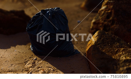 black plastic garbage bags full of trash on the beach 75810895