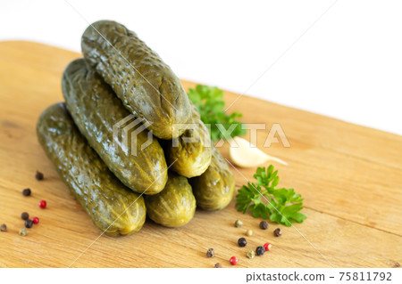 Pickled or fermented homemade cucumbers on wooden board isolated Pickled or fermented homemade cucumbers on wooden board isolated 75811792