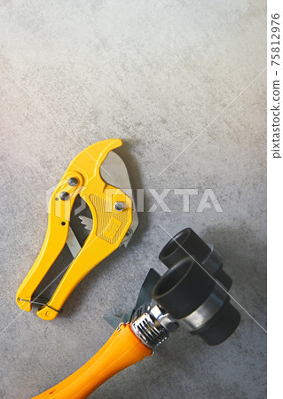 Yellow soldering iron for PVC pipes and pipe cutting scissors, plumbing tools for water supply on a grey background. 75812976