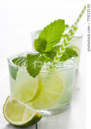 Fresh mojito with lime and mint in glass on white woode table Fresh mojito with lime and mint in glass on white woode table 75813530