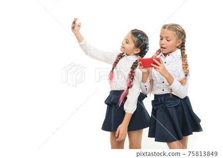 Modern life. Schoolgirls use mobile internet smartphone. 75813849