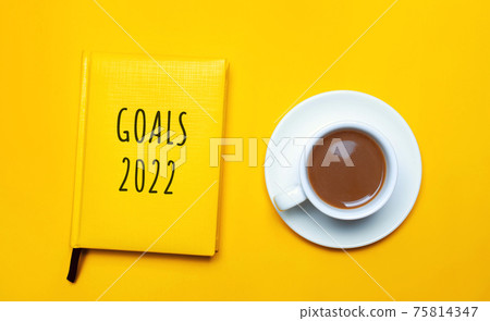 Notebook with the words Goals 2022 and a cup of coffee on a yellow background. Motivation, inspiration. Planning, plans and tasks. New business ideas. Setting goal, target. Notebook with the words Goals 2022 and a cup of coffee on a yellow background. Motivation, inspiration. Planning, plans and tasks. New business ideas. Setting goal, target. 75814347