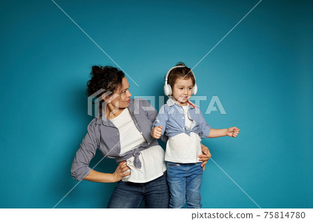 Mother hugging her daughter, posing over blue background 75814780