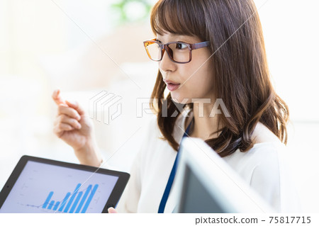 A woman talking with materials on a tablet PC 75817715