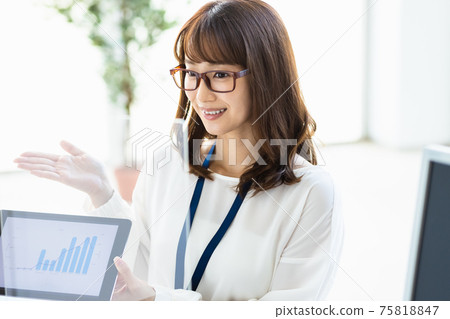 A woman talking over an acrylic partition while showing materials on a tablet PC A woman talking over an acrylic partition while showing materials on a tablet PC 75818847