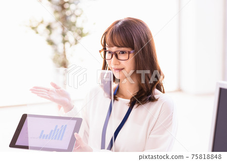A woman talking over an acrylic partition while showing materials on a tablet PC A woman talking over an acrylic partition while showing materials on a tablet PC 75818848