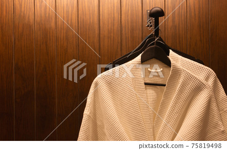 white bathrobes hanging in wooden wardrobe at night white bathrobes hanging in wooden wardrobe at night 75819498