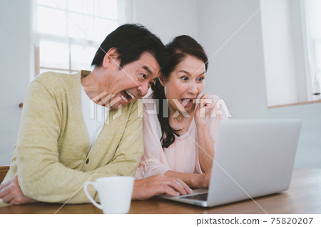 A mature couple who is surprised to see the computer screen A mature couple who is surprised to see the computer screen 75820207