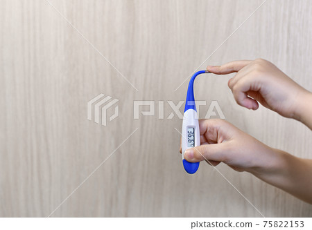 A digital thermometer with a flexible tip in hand. 75822153