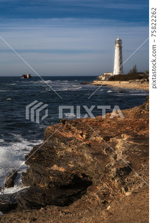 Lone beacon guards the ships. The lighthouse shows the way for boats. Wrecked ship lays nearby 75822262