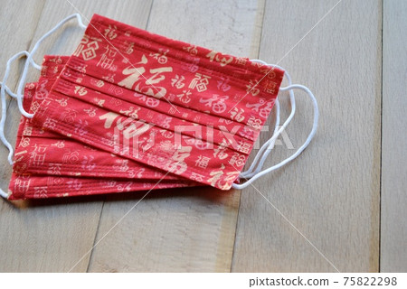 Red color mask with Chinese Luck character in different writing styles on wooden background for social distancing of Chinese New Year in February. Copy space Red color mask with Chinese Luck character in different writing styles on wooden background for social distancing of Chinese New Year in February. Copy space 75822298