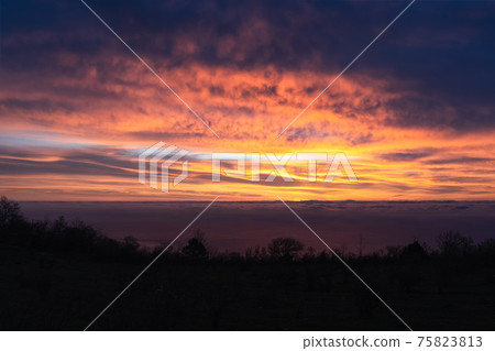 Amazingly beautiful sunrise over sea. breathtaking colors in sky from rising sun. Silhouette of coast against background of glowing clouds 75823813