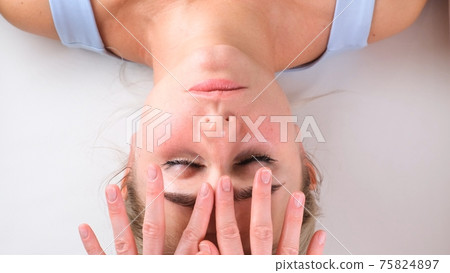 Facial massage beauty treatment. Close up of a young womans face lying on back, getting face lifting 75824897