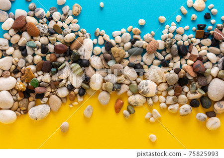 Sea pebbles on a blue and yellow background 75825993