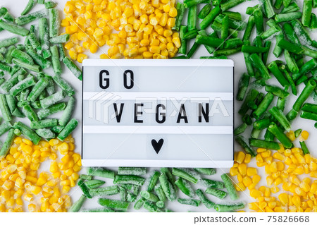 Lightbox with text GO VEGAN frozen vegetables food of yellow corn, green beans. Harvest Food preservation for winter. 75826668
