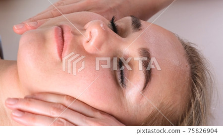 Beautiful woman in salon having facial massage. 75826904