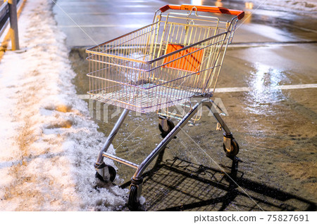 An abandoned shopping cart standing on the street near supermarket in the winter. An abandoned shopping cart standing on the street near supermarket in the winter. 75827691