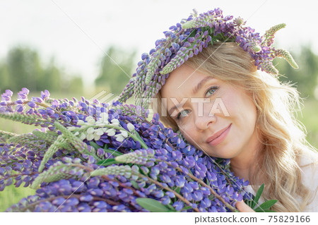A hippy girl holding bouquet of wildflowers in her hands. Girl hid her face behind bouquet of lupins A hippy girl holding bouquet of wildflowers in her hands. Girl hid her face behind bouquet of lupins 75829166