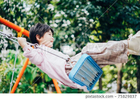 A boy riding a swing alone A boy riding a swing alone 75829837