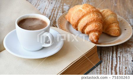 Cup of coffee and croissant on a wooden table 75830263