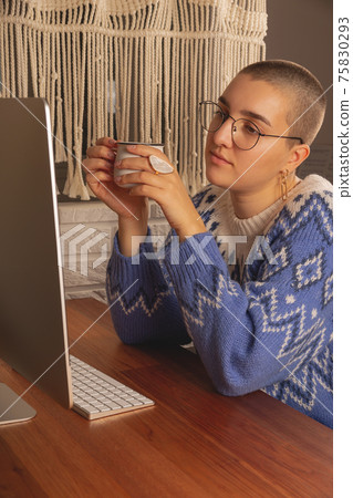 The woman works from home at the computer. Real people during a pandemic and a new reality The woman works from home at the computer. Real people during a pandemic and a new reality 75830293
