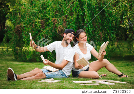 Young man and woman playing giant dominoes in the Park on the grass. Young man and woman playing giant dominoes in the Park on the grass. 75830593
