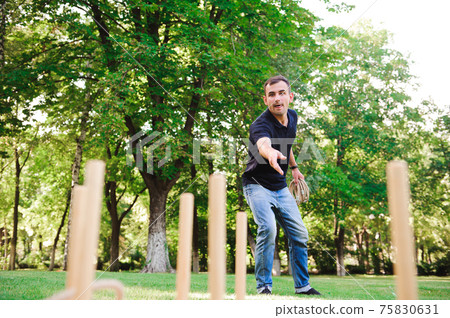 Boy playing a game throwing rings outdoors in summer park. Boy playing a game throwing rings outdoors in summer park. 75830631
