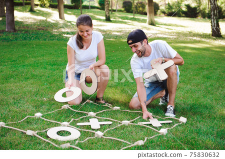 Big Tic Tac Toe game. Guy and girl playing outdoors. Big Tic Tac Toe game. Guy and girl playing outdoors. 75830632