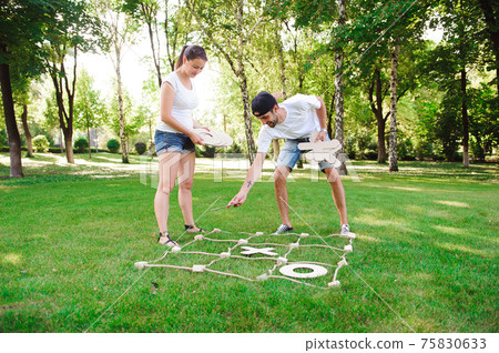Boy and girl playing tic-tac-toe in the park. Boy and girl playing tic-tac-toe in the park. 75830633