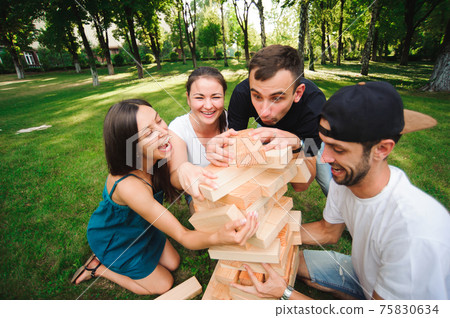 Friends playing board game outdoors in the park. Friends playing board game outdoors in the park. 75830634