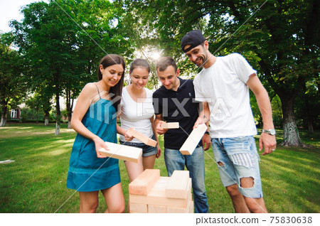 Friends playing board game outdoors in the park. Friends playing board game outdoors in the park. 75830638
